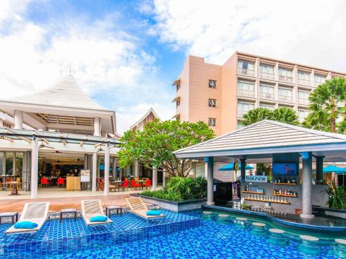 芭东海滩Grand Mercure Phuket Patong的一个带椅子的游泳池和一间酒店