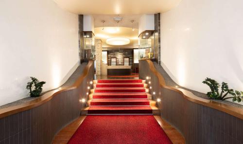 戈里齐亚贝斯特韦斯特格瑞泽雅宫酒店的走廊上铺有红地毯,楼梯上配有灯