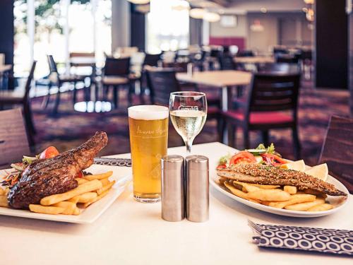 奥兰治奥兰治美居酒店的一张桌子,上面放着两盘食物和一杯啤酒