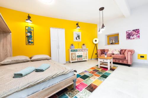 罗维尼Apartman Paulina的卧室拥有黄色的墙壁,配有一张床和一张沙发