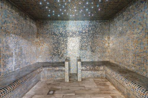 克罗默克罗默乡村俱乐部钻石度假酒店的瓷砖浴室设有长凳和窗户。