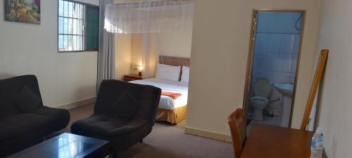 朱巴Lamerinn Hotel Juba的一间卧室配有一张床、一把椅子和一张桌子