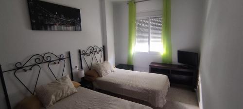 加苏莱斯堡Casa Gazules的一间卧室设有两张床、一台电视和一扇窗户。