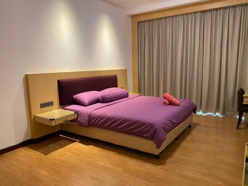 古晋The Floorspace Imperial Suites Apartment的一间卧室配有一张带紫色床单的床和窗户。