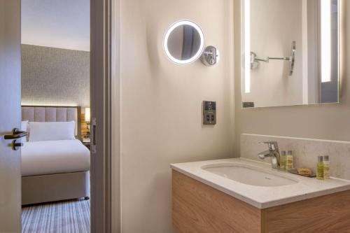 伦敦伦敦切尔西希尔顿逸林酒店的一间带水槽、床和镜子的浴室