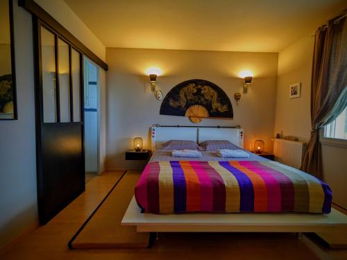 蒙梅利扬Le Belvédère : chambres et table d'hôtes的一间卧室配有一张带彩色条纹毯子的床