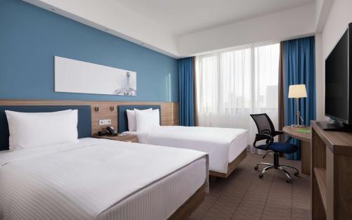 阿斯塔纳Hampton By Hilton Astana Triumphal Arch的一间酒店客房,设有两张床和电视