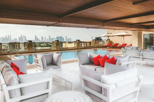 迪拜DoubleTree by Hilton Dubai Al Jadaf的一个带白色椅子的屋顶露台和游泳池