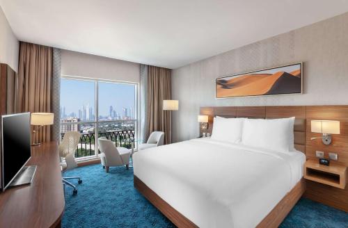 迪拜DoubleTree by Hilton Dubai Al Jadaf的配有一张床、一张书桌和一扇窗户的酒店客房