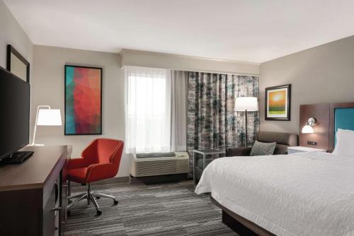 尚佩恩Hampton Inn Champaign Southwest的酒店客房配有一张床、一张桌子和一把椅子。