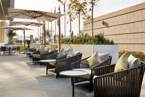 科威特Hilton Garden Inn Kuwait的庭院里摆放着一排桌椅和遮阳伞