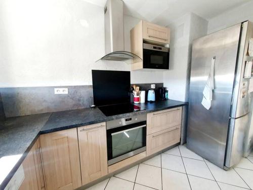 马里尼亚讷Appart 70m² plein sud的厨房配有不锈钢冰箱和橱柜