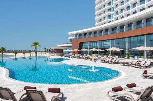 拉斯阿尔卡麦Hampton by Hilton Marjan Island的一座游泳池位于酒店前,设有椅子和一座建筑