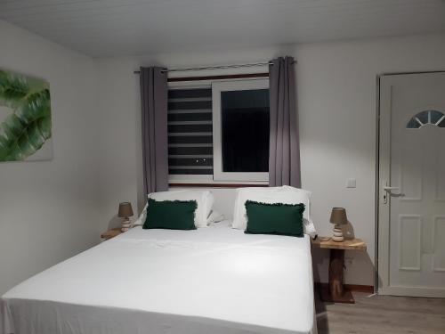 HauruFare Mihiau 2的卧室内的一张带两个绿色枕头的白色床