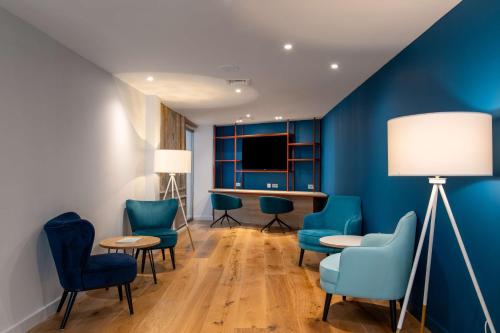 坎特伯雷Hampton by Hilton Canterbury的一间设有蓝色椅子和桌子的等候室