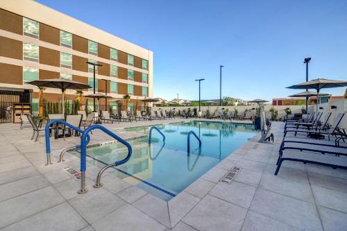 拉斯维加斯Home2 Suites By Hilton Las Vegas Northwest的一座带椅子的游泳池以及一座建筑
