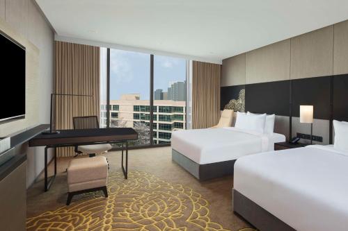 班加罗尔Hilton Bengaluru Embassy Manyata Business Park的酒店客房设有两张床、一张桌子和一台电视。