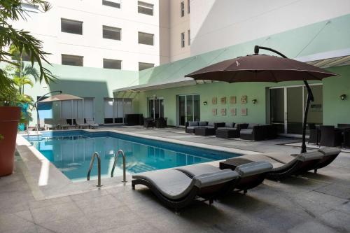 韦拉克鲁斯Hampton by Hilton Veracruz Boca Del Rio的一座带椅子和遮阳伞的游泳池位于大楼旁