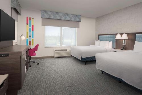 德尔雷比奇Hampton Inn Delray Beach的酒店客房设有两张床和一台平面电视。