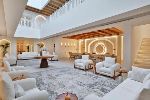 多哈Maysan Doha, LXR Hotels & Resorts的一间设有白色家具和楼梯的大客厅