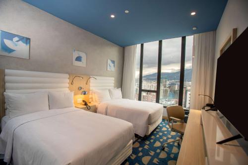 基多Hampton By Hilton Quito La Carolina Park的酒店客房设有两张床和大窗户。
