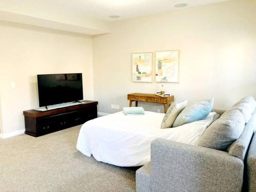 卡尔加里Mahogany Escape - Your Calgary Oasis的一间卧室配有一张床、一台电视和一张沙发