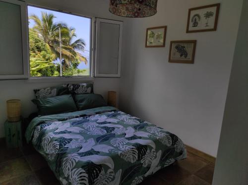 GallochatBungalow WAVES vue mer avec parking privé的一间卧室设有一张床,窗户拥有棕榈树