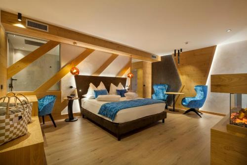安达洛Adler Hotel Wellness & Spa - Andalo的一间卧室配有一张床和两张蓝色椅子