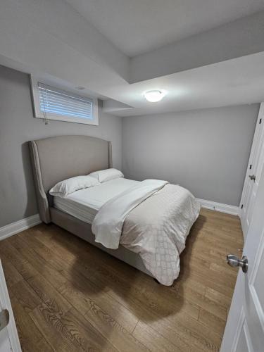 多伦多Basement Apartment in Luxury Beach House的一间卧室设有一张床和一个窗户,铺有木地板
