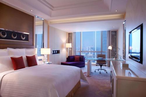 广州Guangzhou Marriott Hotel Tianhe的酒店客房设有一张大床和一张书桌。