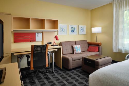 安娜堡TownePlace Suites Ann Arbor的酒店客房配有一张床、一张书桌和一张沙发。