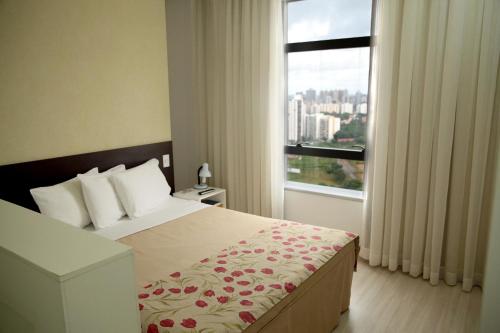 萨尔瓦多Iguatemi Business & Flat by Avectur的一间卧室设有一张床和一个大窗户