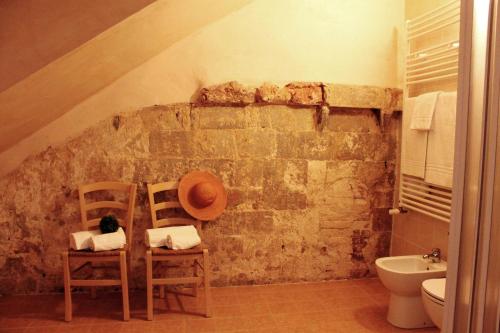 蒙特里久尼Ostello Contessa Ava dei Lambardi的一间带两把椅子和石墙的浴室