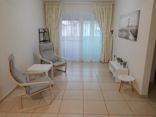 XylophaghouLarnaca Xylophagou 2-bedroom apartment with a shaded terrace的客厅配有椅子、桌子和窗户
