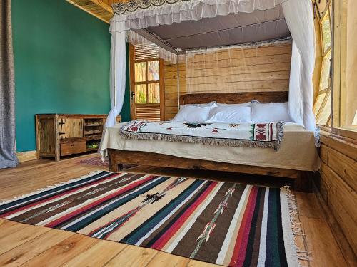 伊林加Jabali Mountain Cabin的一间卧室配有一张天蓬床和地毯。
