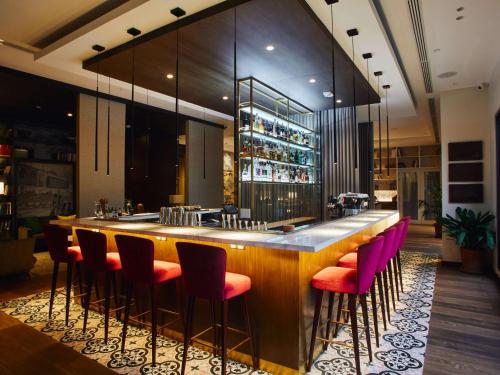 利马Manto Hotel Lima - MGallery的餐厅内的酒吧,配有粉红色的椅子