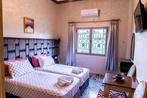 廷吉尔HOTEL LA VALLEE DES KASBAHS CHEZ ILYAS的一间卧室配有一张床、一张沙发和一个窗口