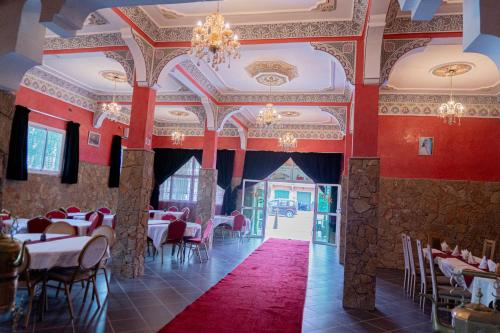 廷吉尔HOTEL LA VALLEE DES KASBAHS CHEZ ILYAS的餐厅拥有红色的墙壁和桌椅