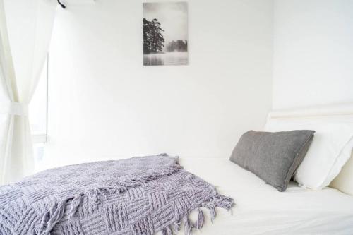 雅加达Comfy Casa的白色卧室,配有一张带灰色毯子的床