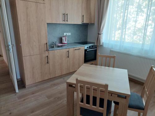 上米托Penzion ČESKÁ FARMA的厨房配有木制橱柜、桌子和桌椅