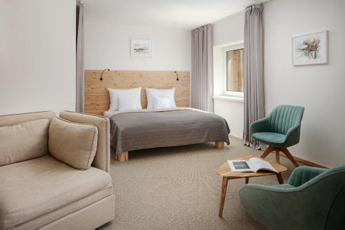 哈拉霍夫Ski & Spa hotel BELLEVUE的一间卧室配有一张床、一张沙发和一把椅子