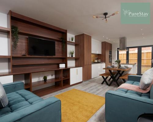 曼彻斯特Stunning 5 Bed House By PureStay Short Lets & Serviced Accommodation Manchester With Parking的客厅配有2张蓝色沙发和电视