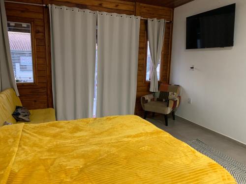 佩尼亚Canto Gira Sol - Suíte Flor的一间卧室配有一张黄色的大床和一把椅子