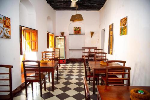 Stone TownLa Neisha Hotel Zanzibar的餐厅设有木桌和椅子,铺有 ⁇ 木地板