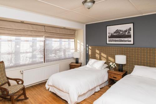 纳塔列斯港Bories - Boutique Guest House的一间卧室设有两张床、一把椅子和一个窗户。