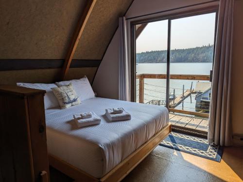 Heriot BayJade Resort-Oceanfront Suites in Gowlland Harbour的一间卧室配有一张带毛巾的床和大窗户