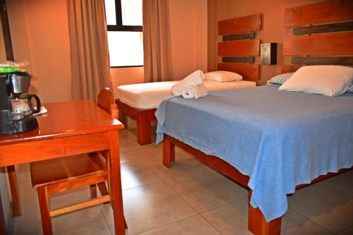 蓬塔雷纳斯Hotel Cabinas Midey的酒店客房设有两张床、一张桌子和一张书桌。