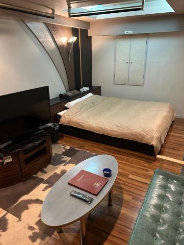 横滨Hotel AKAIKUTSU - Adult Only的客房设有1张床、1张桌子和1台电视。