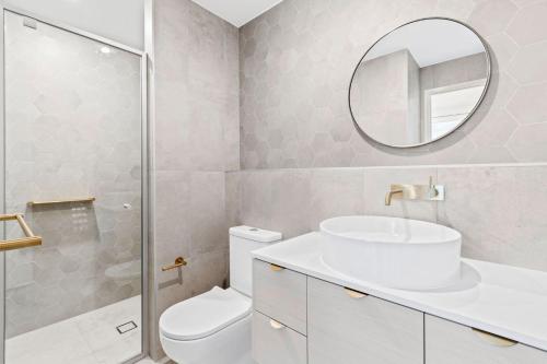 巴特曼斯贝Ohana Apartments 103的一间带卫生间、水槽和镜子的浴室