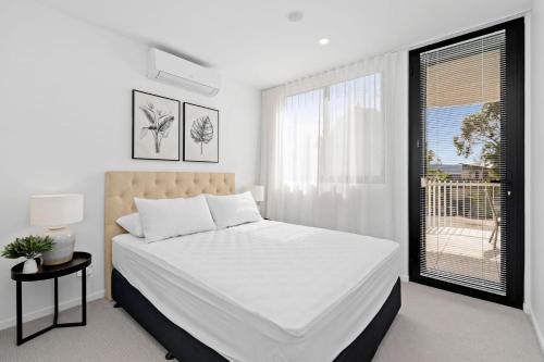 巴特曼斯贝Ohana Apartments 103的白色的卧室设有一张大床和一个窗户